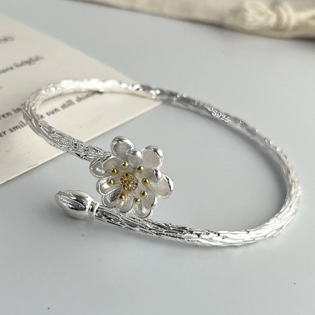 Silver bracelet with a floral design on a light gray surface