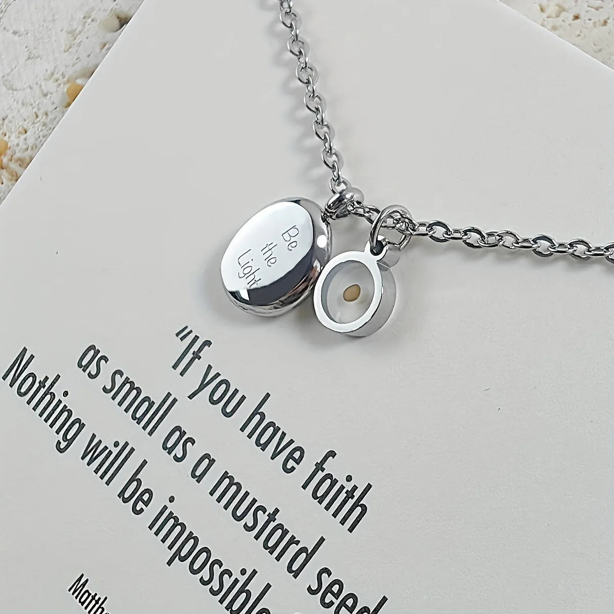 Silver necklace with two charms on a card with inspirational quote