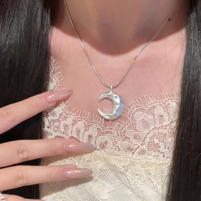 Silver crescent moon necklace on a person wearing a lace garment.