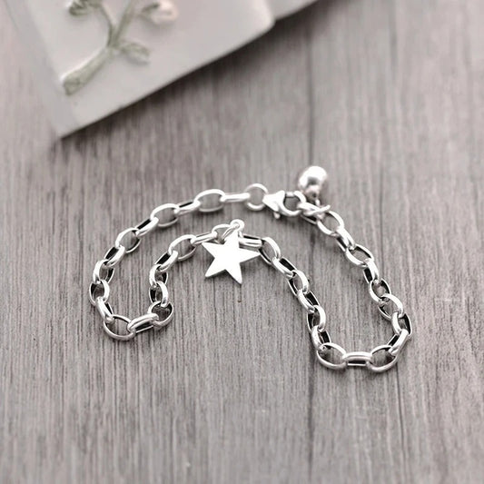 Silver chain bracelet with a star charm on a wooden surface
