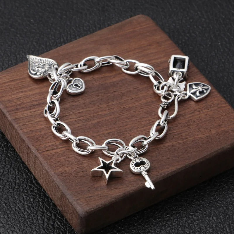 Silver charm bracelet with various charms on a wooden block