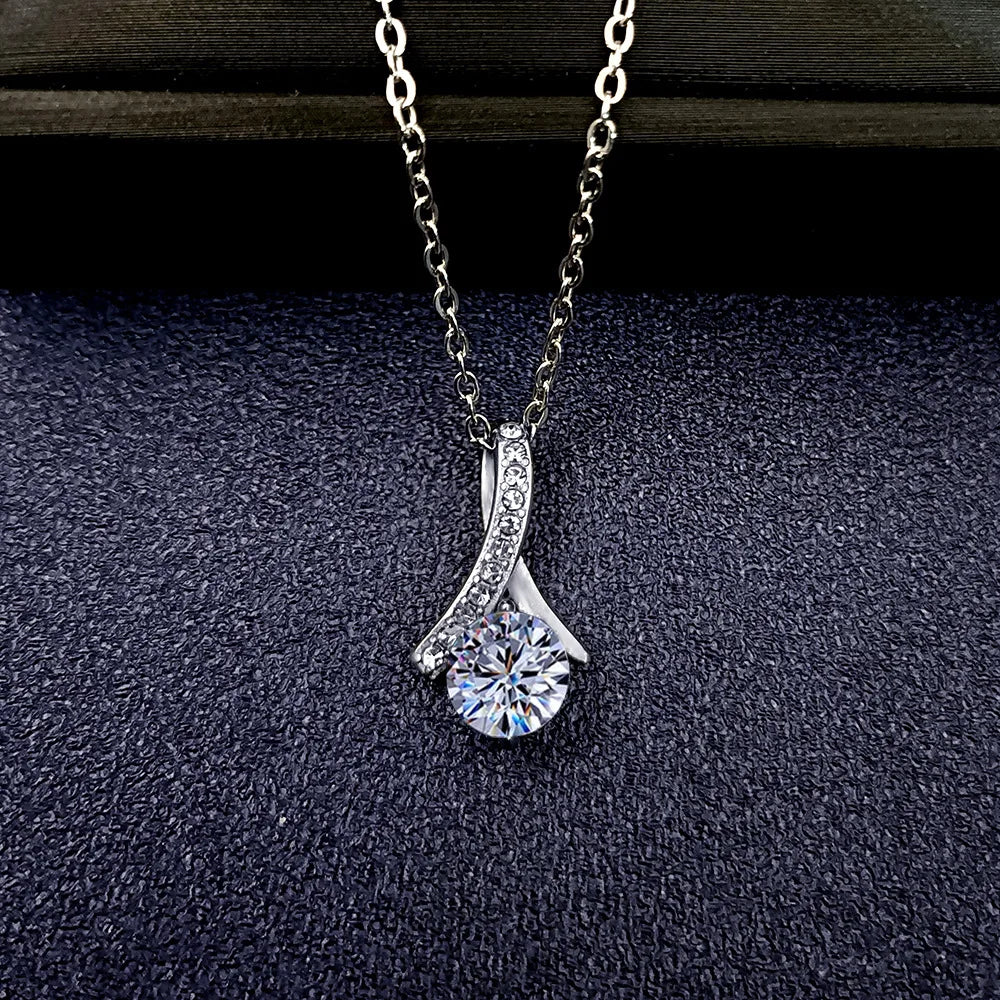 Silver necklace with a diamond pendant on a dark textured surface