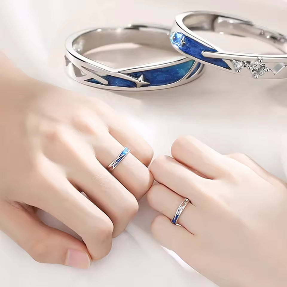 Two hands wearing silver rings with blue accents on a white background