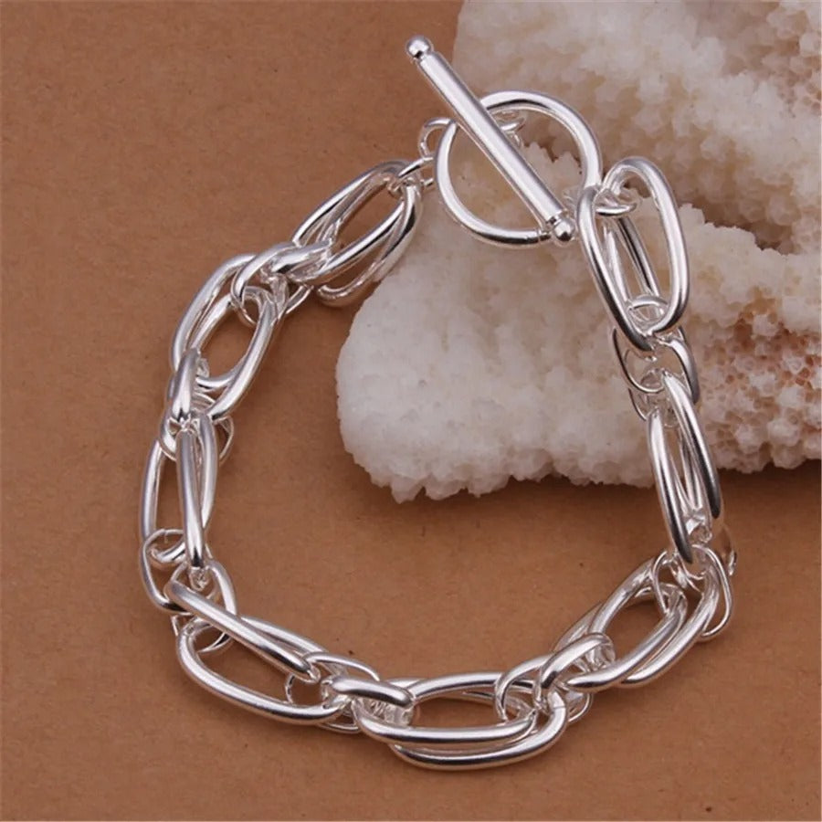 Silver chain bracelet on a brown background with a shell