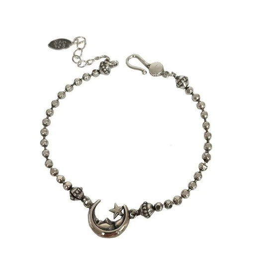 Silver bracelet with moon and star charm on a white background