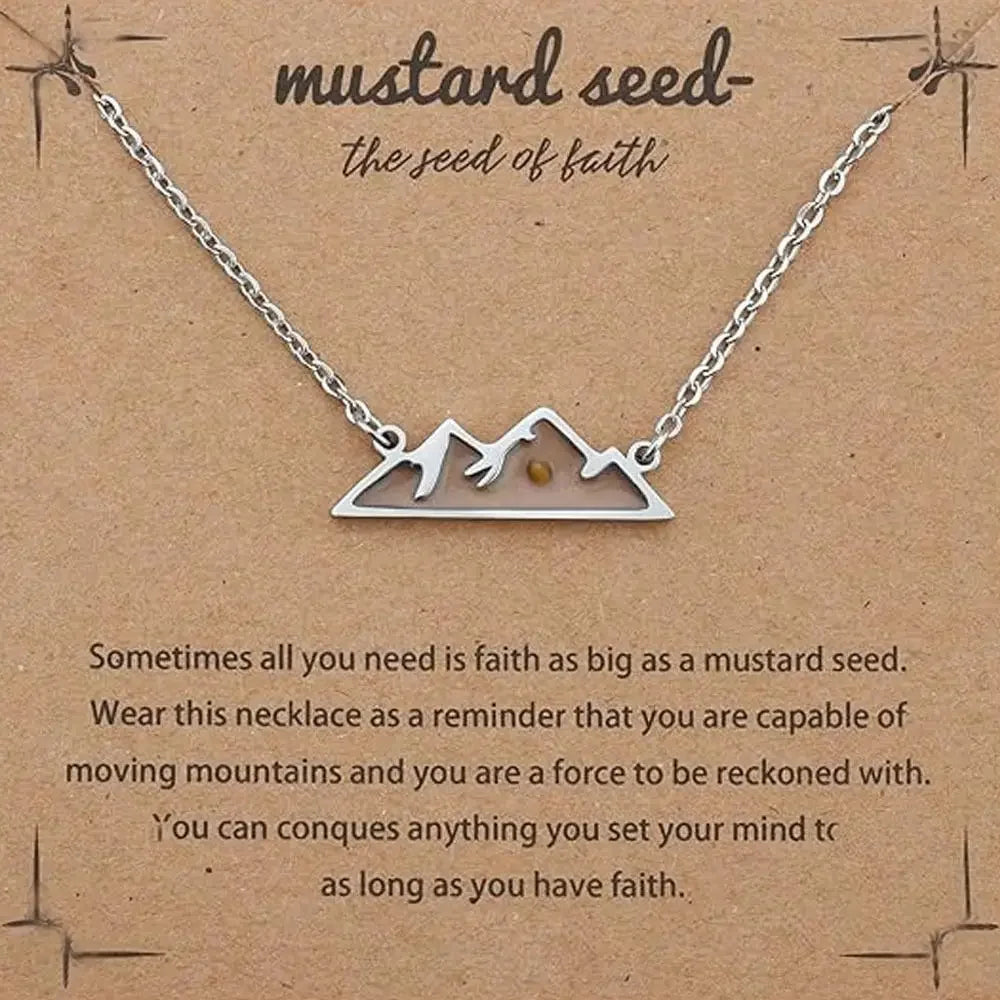 A silver mountain-shaped necklace with a mustard seed pendant, displayed on a brown kraft card with inspirational text.