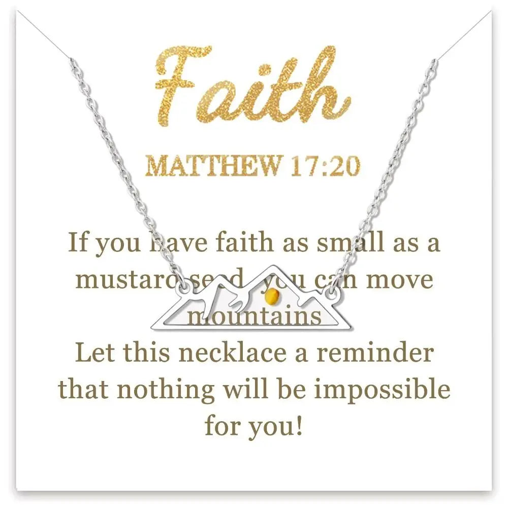 Silver mountain-shaped necklace with a small gold gemstone, displayed on a white card with gold text reading 'Faith' and 'Matthew 17:20' plus a supportive message.