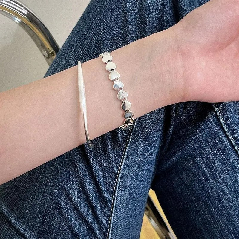 Person wearing a silver bracelet with a beaded design on a blue denim background