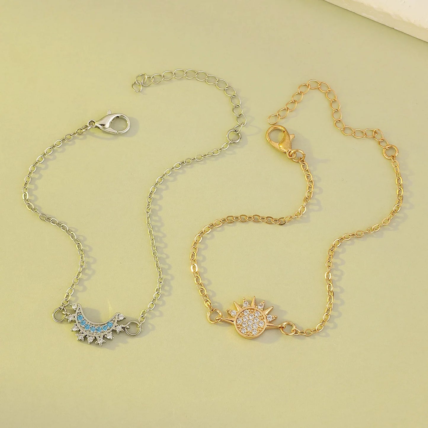 A gold and silver bracelet with a moon and a star lay on the ground.