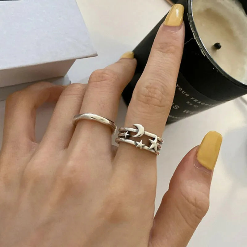 Hand wearing two silver rings with a candle in the background