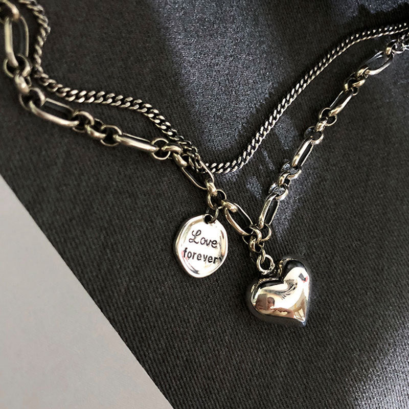 Necklace with heart charm and 'Love forever' tag on a dark fabric background