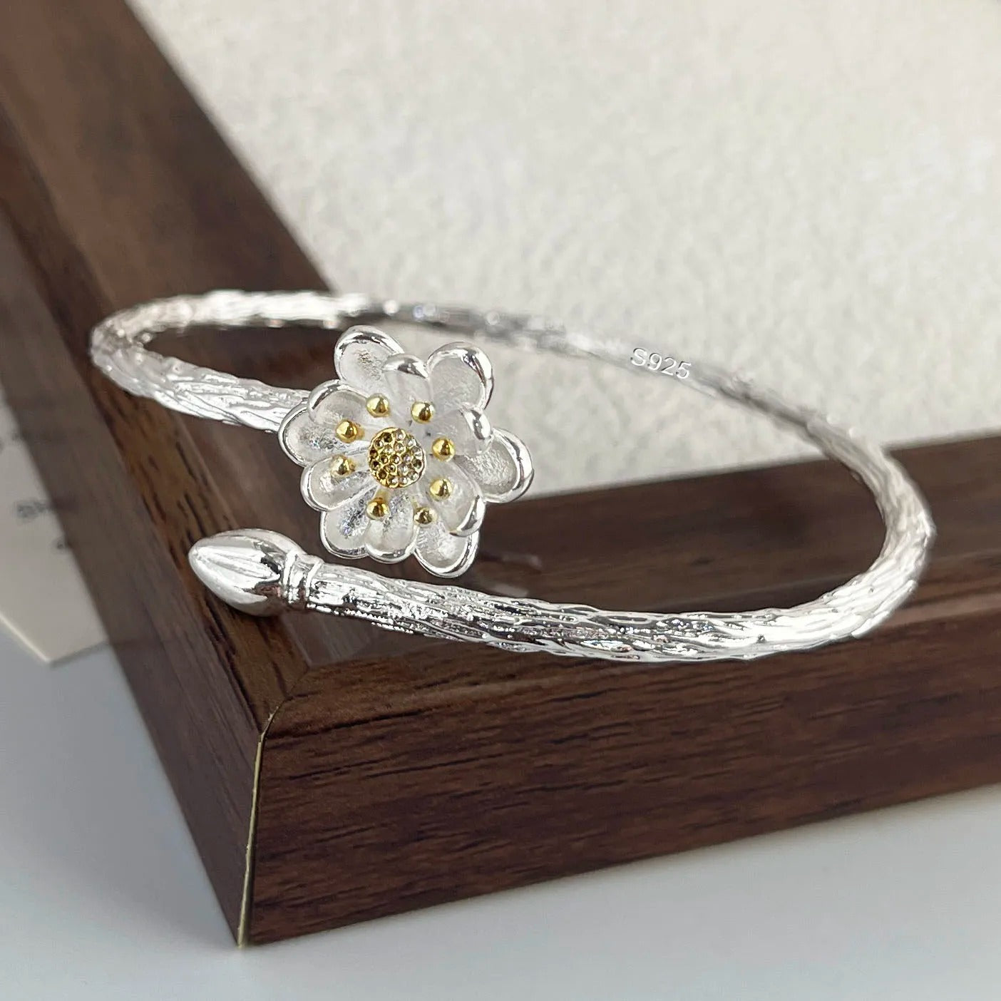 Silver bracelet with a floral design on a wooden surface