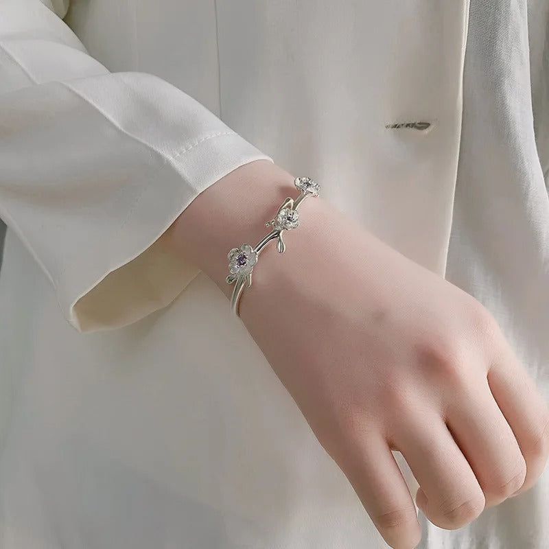 Silver bracelet on a person's wrist with a plain background
