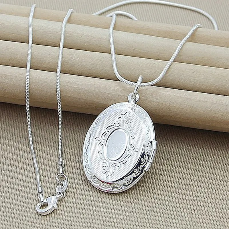 Silver locket necklace on a beige surface
