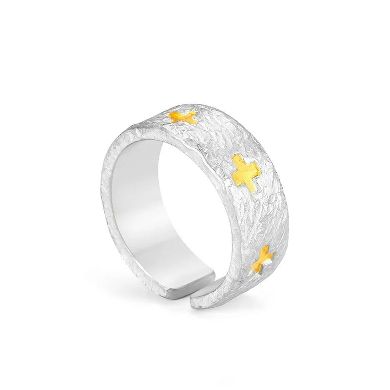 Silver ring with gold crosses on a white background