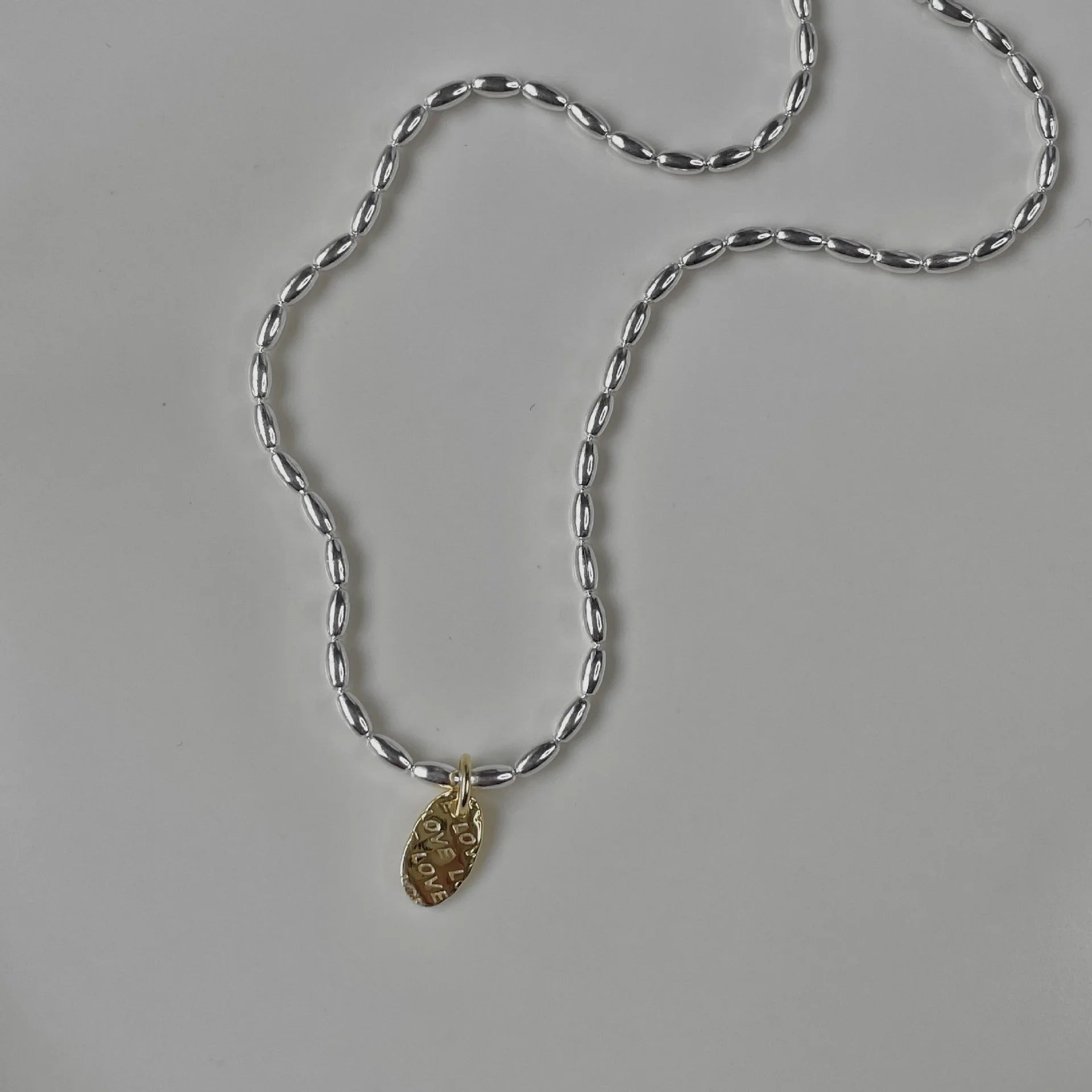 Silver chain necklace with a gold pendant on a gray background