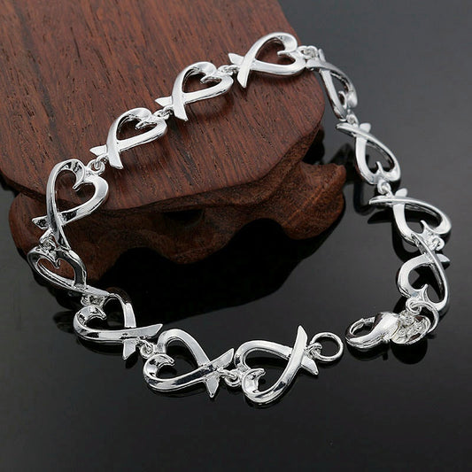 Silver bracelet with heart and infinity designs on a dark surface