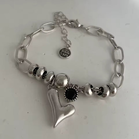 Silver bracelet with heart charm and beads on a white background