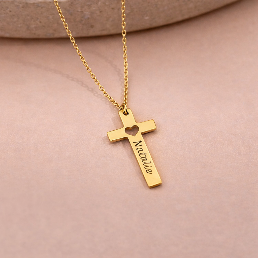 Gold cross necklace with 'Natalie' engraved on a pink background