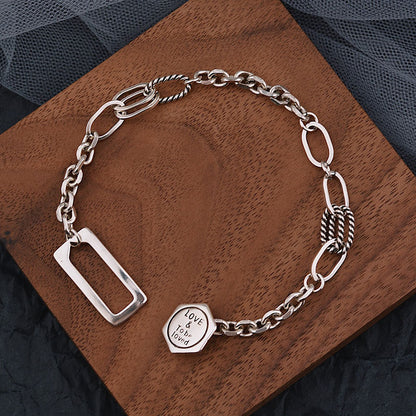 Silver chain bracelet with heart-shaped tag on a wooden surface