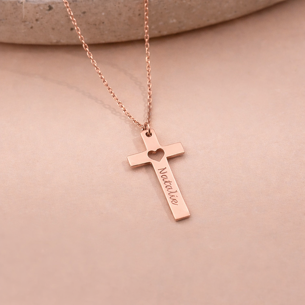 Rose gold cross necklace with 'Natalie' engraved on a beige background