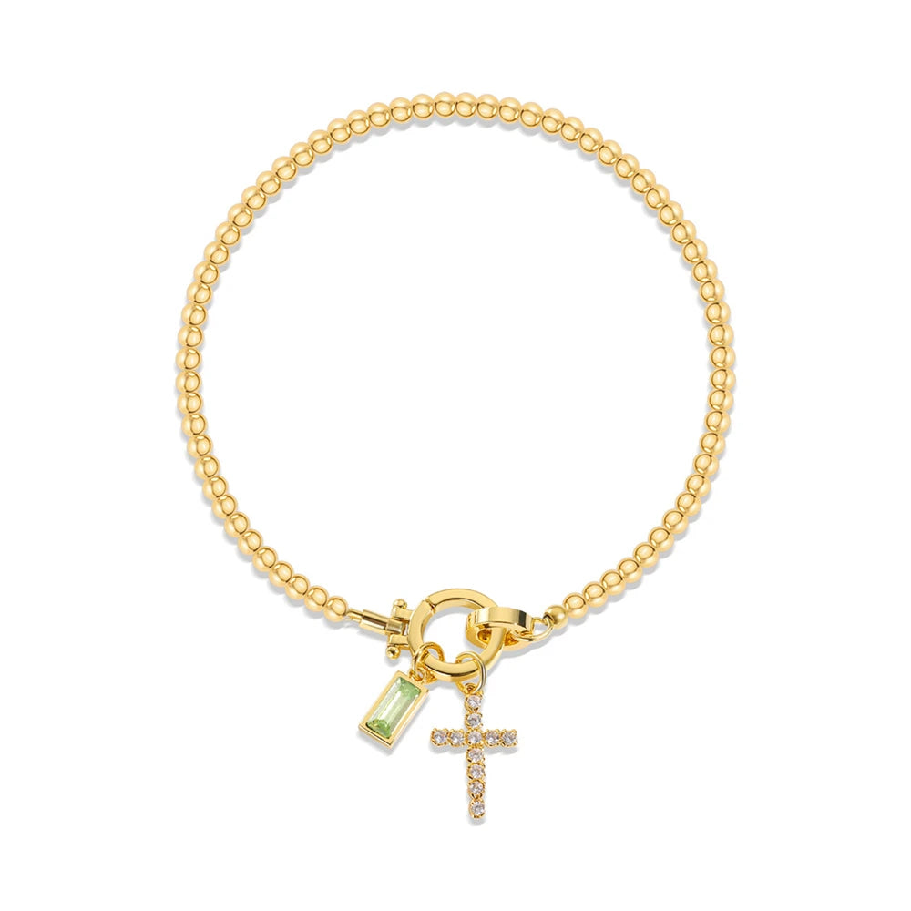 Gold bracelet with charm and cross pendant on a white background