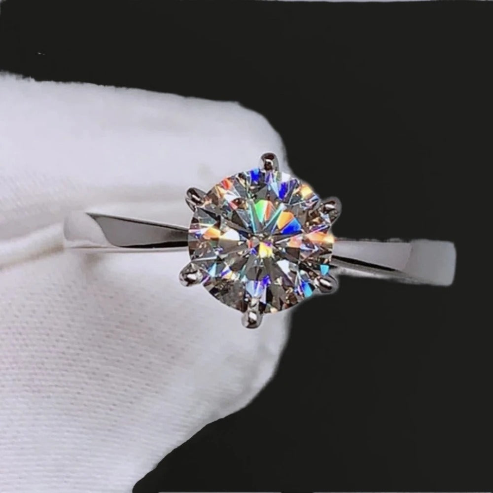 Silver ring with a large diamond on a white surface