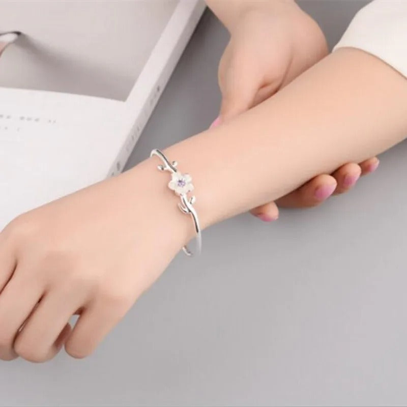 Silver bracelet on a wrist with a neutral background