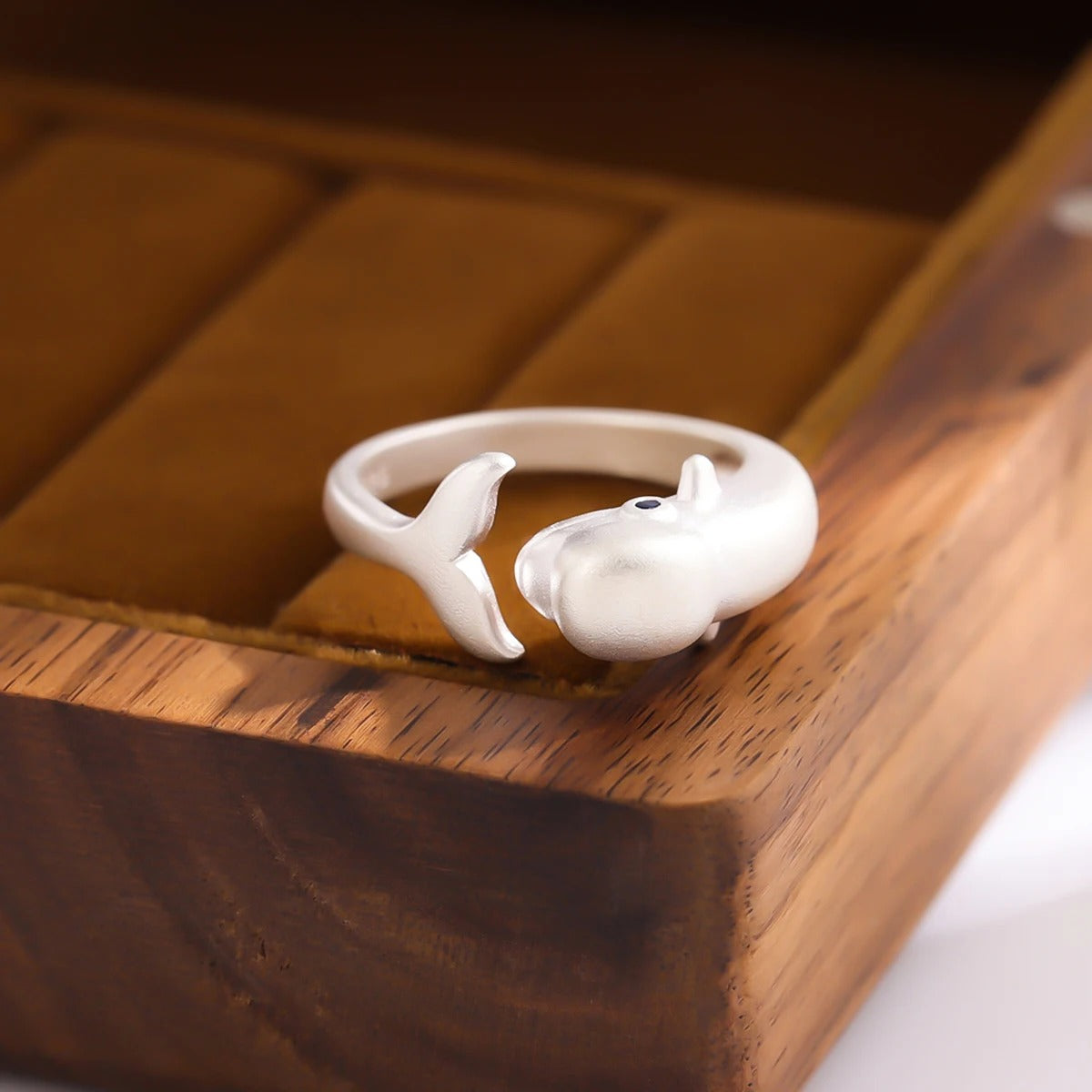 White ceramic ring with a small figure on a wooden surface