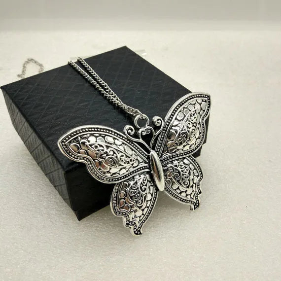 Butterfly-shaped pendant on a chain with a black box in the background