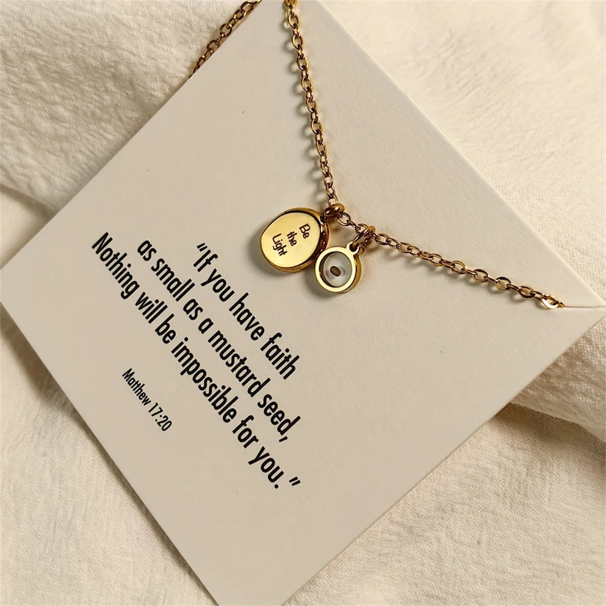 Gold necklace with two charms on a card with a motivational quote