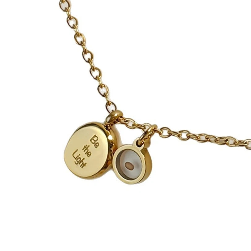 Gold necklace with two charms on a white background