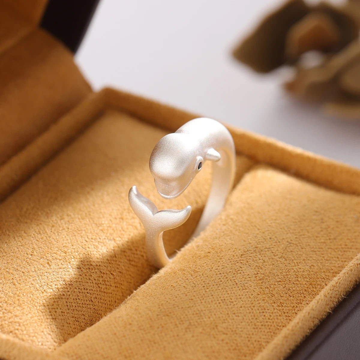 Silver dolphin-shaped ring on a yellow jewelry box