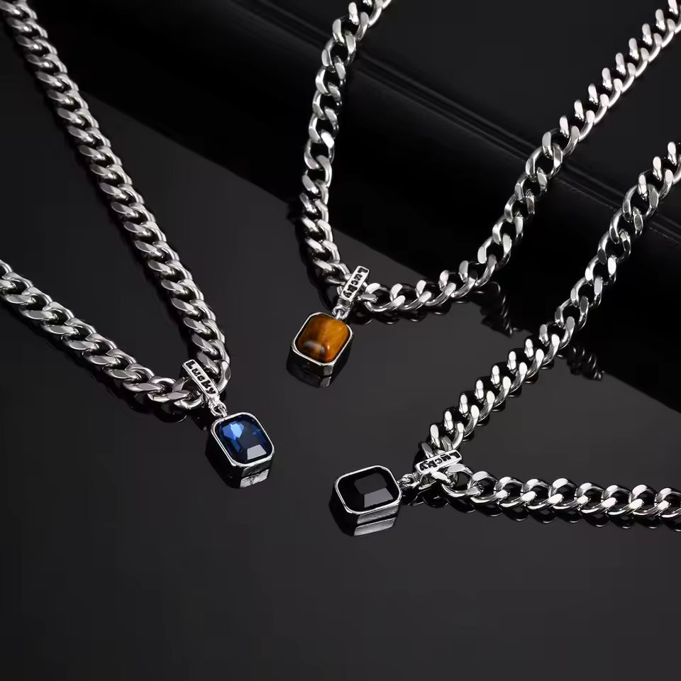 Three silver chain necklaces with embedded gemstones on a black background