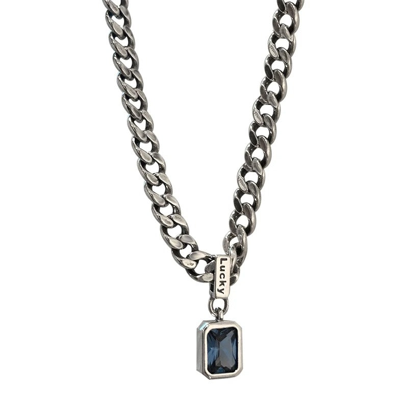 Silver chain necklace with a blue gemstone pendant on a white background