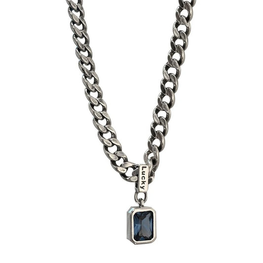 Silver chain necklace with a blue gemstone pendant on a white background