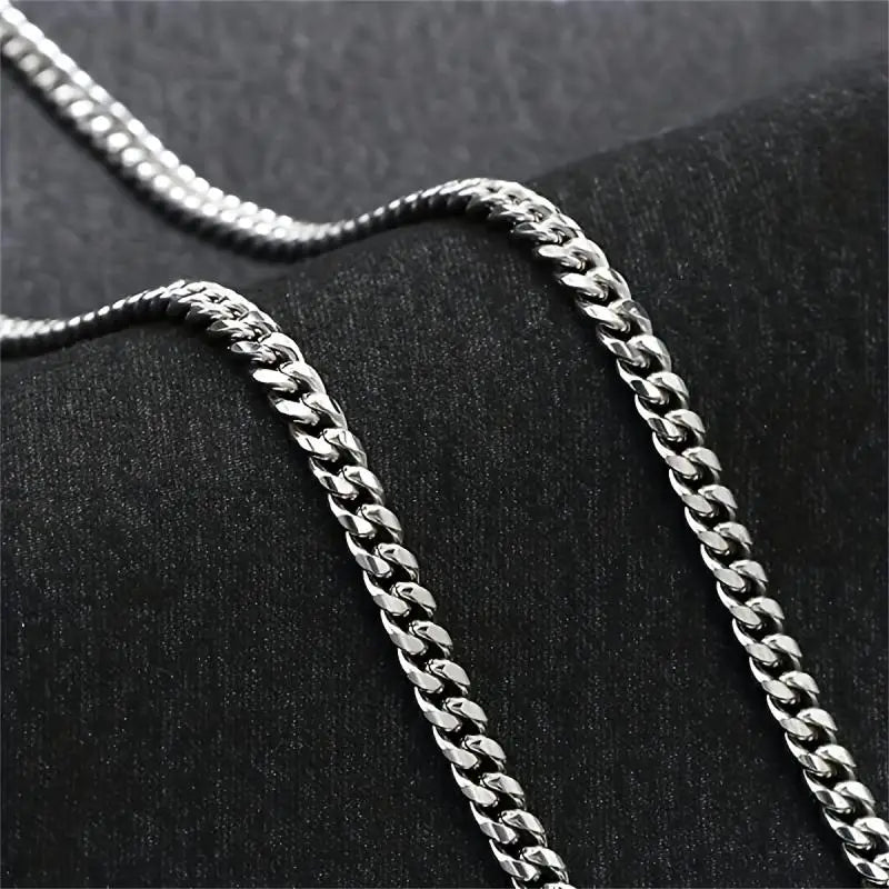 Two silver chain necklaces on a textured black surface