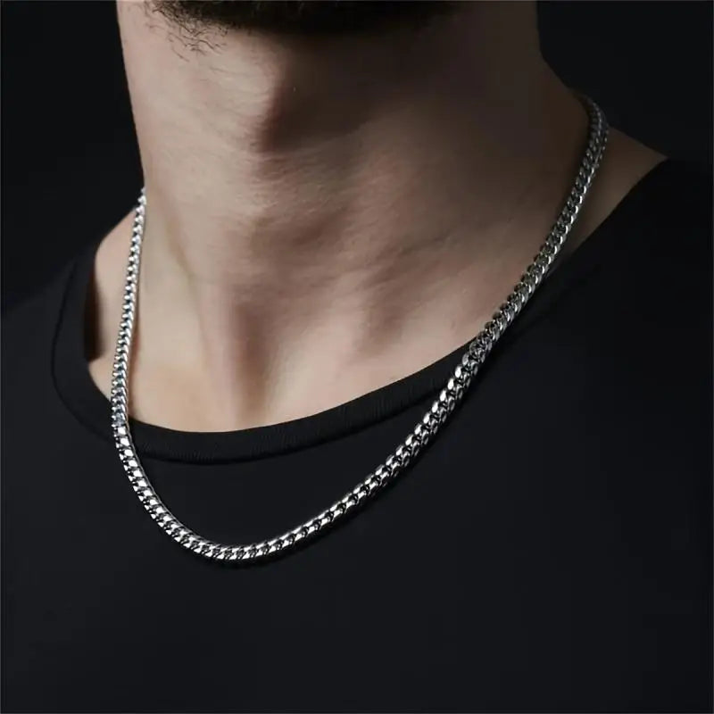Silver chain necklace worn by a person on a black background