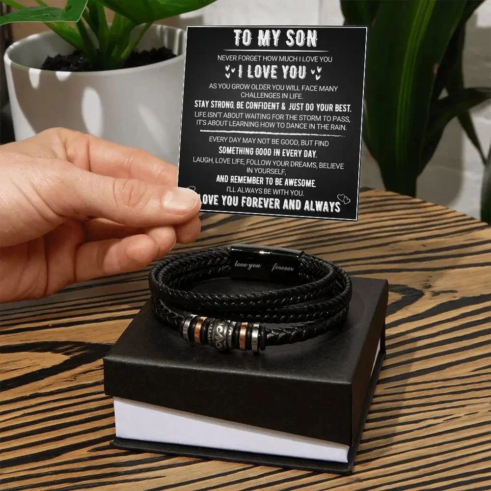 Black card with motivational message and black braided bracelets on a wooden surface.