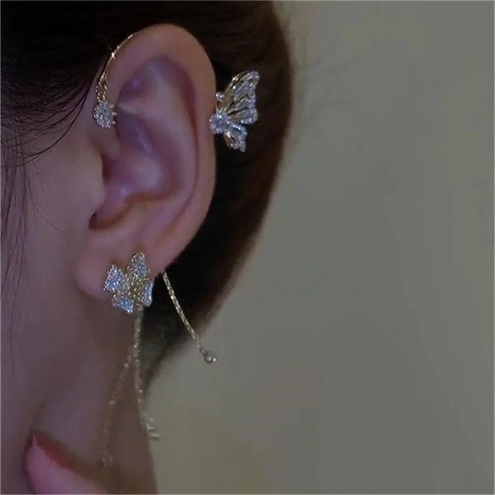 Close-up of an ear with butterfly-shaped earrings on a neutral background