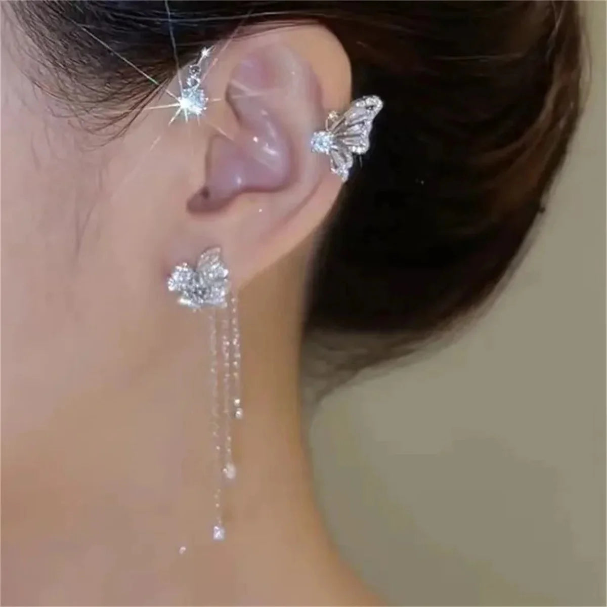 Close-up of an ear wearing butterfly-shaped earrings with a blurred background