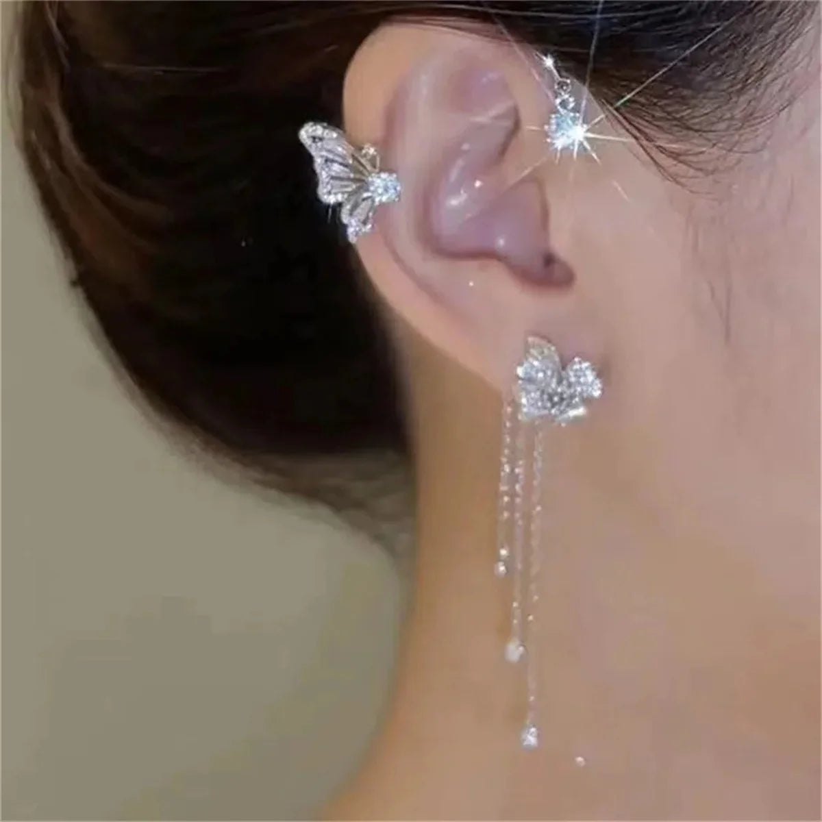 Close-up of an ear with a silver earring on a neutral background
