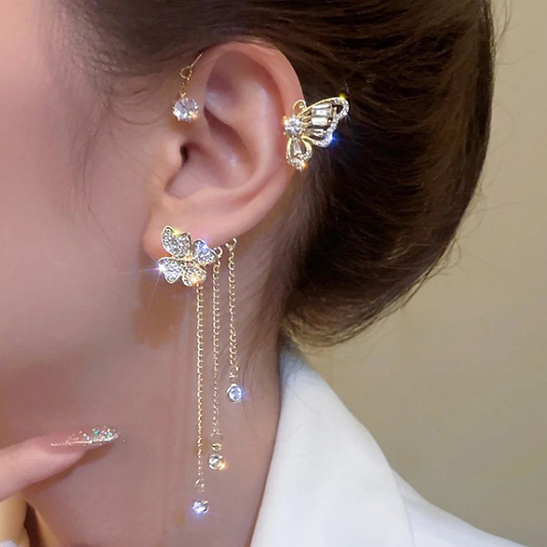 Close-up of an ear with butterfly-shaped earrings on a neutral background