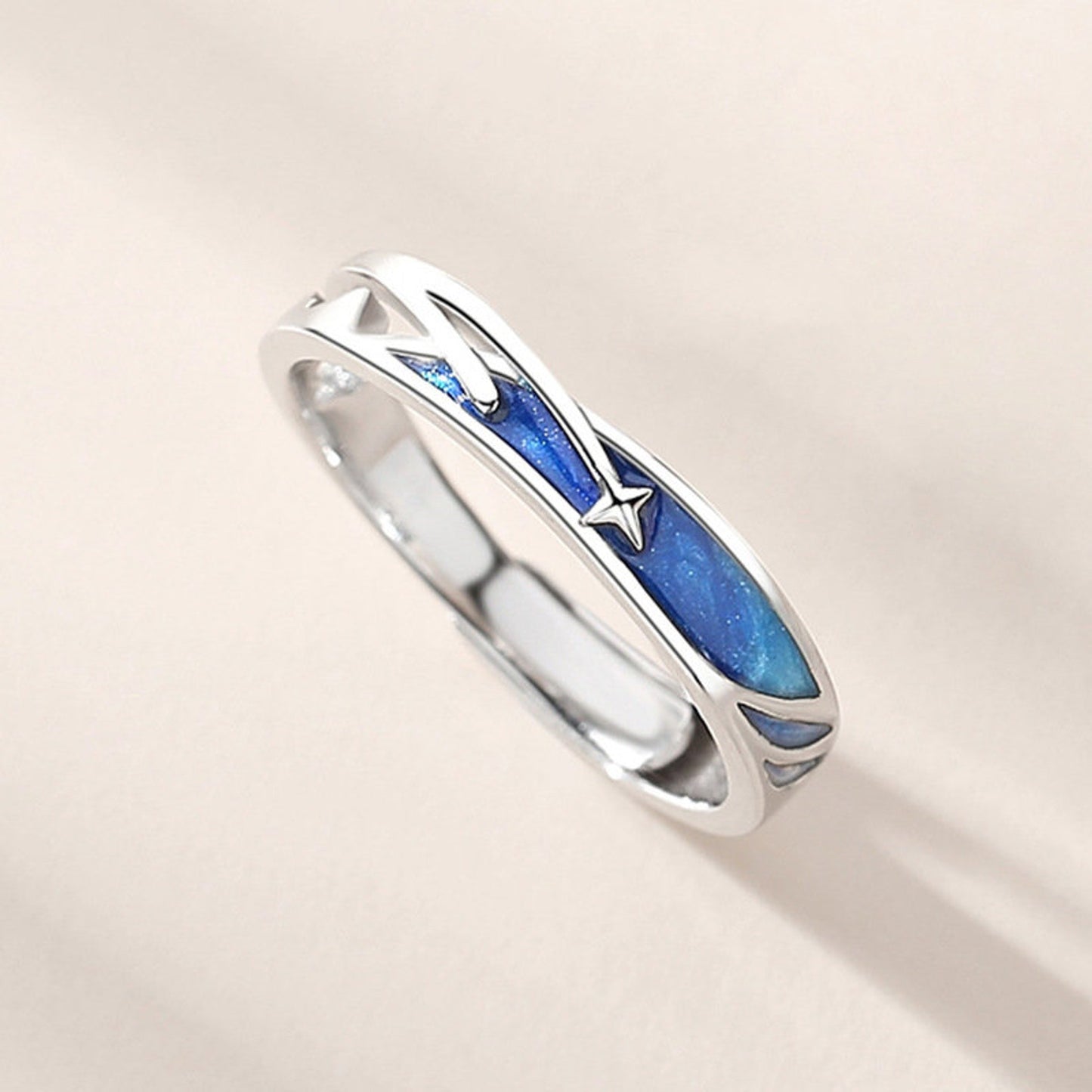 Silver ring with blue inlay on a light beige background