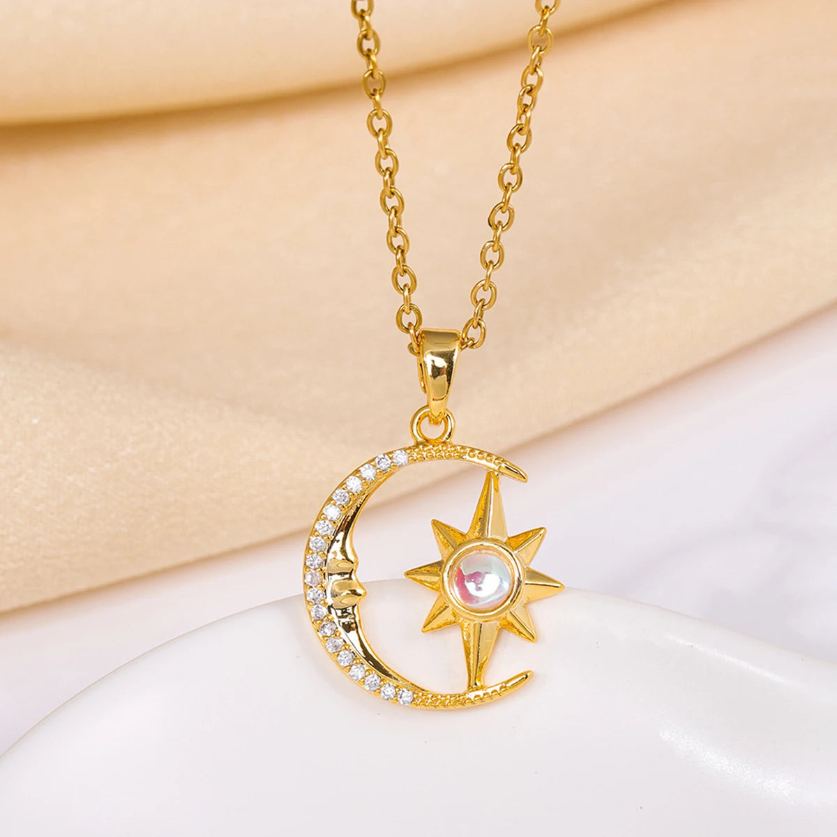 Gold necklace with a moon and star pendant on a beige and white background