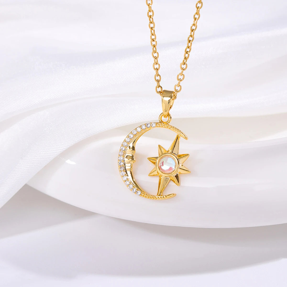Gold necklace with a sun and moon pendant on a white background