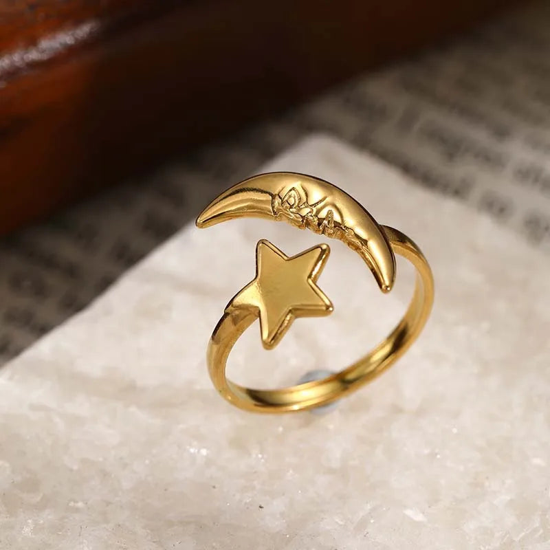 Gold ring with moon and star design on a textured surface
