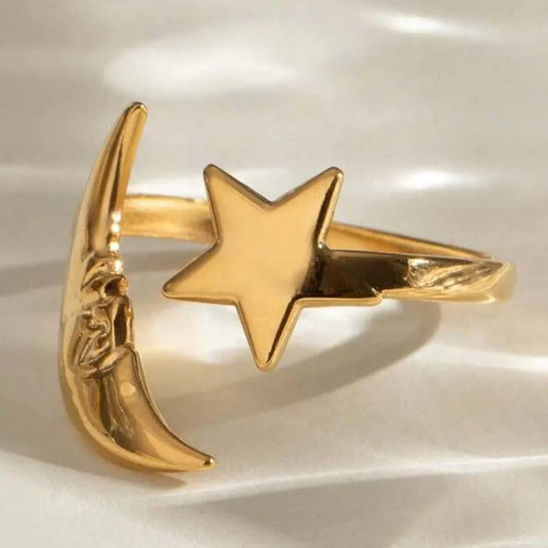 Gold ring with star and moon design on a light background