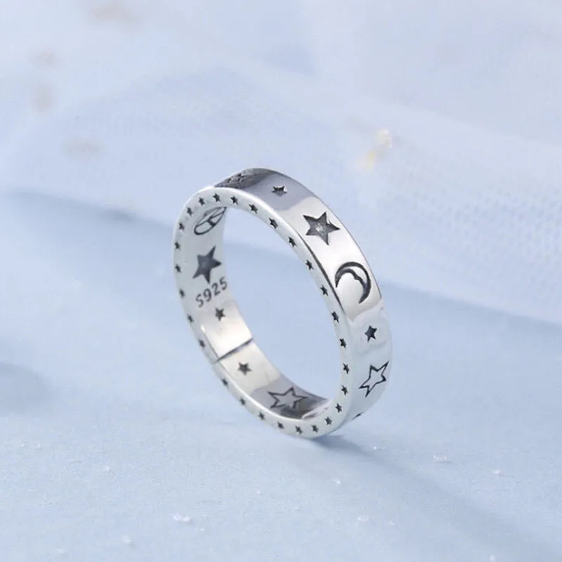 Silver ring with star and moon designs on a light blue background