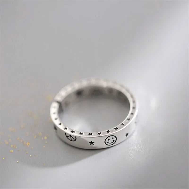 Silver ring with engraved symbols on a light gray background